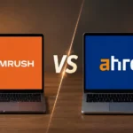 Semrush vs Ahrefs for Freelancers in 2026 Two open laptops facing each other on a wooden desk in warm lamplight, the left screen showing the Semrush logo in white on orange and the right showing the Ahrefs logo in white and orange on blue, separated by a bright VS divider.